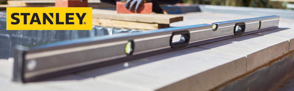 Eine Wasserwaage liegt auf einer Mauer auf einer Baustelle.